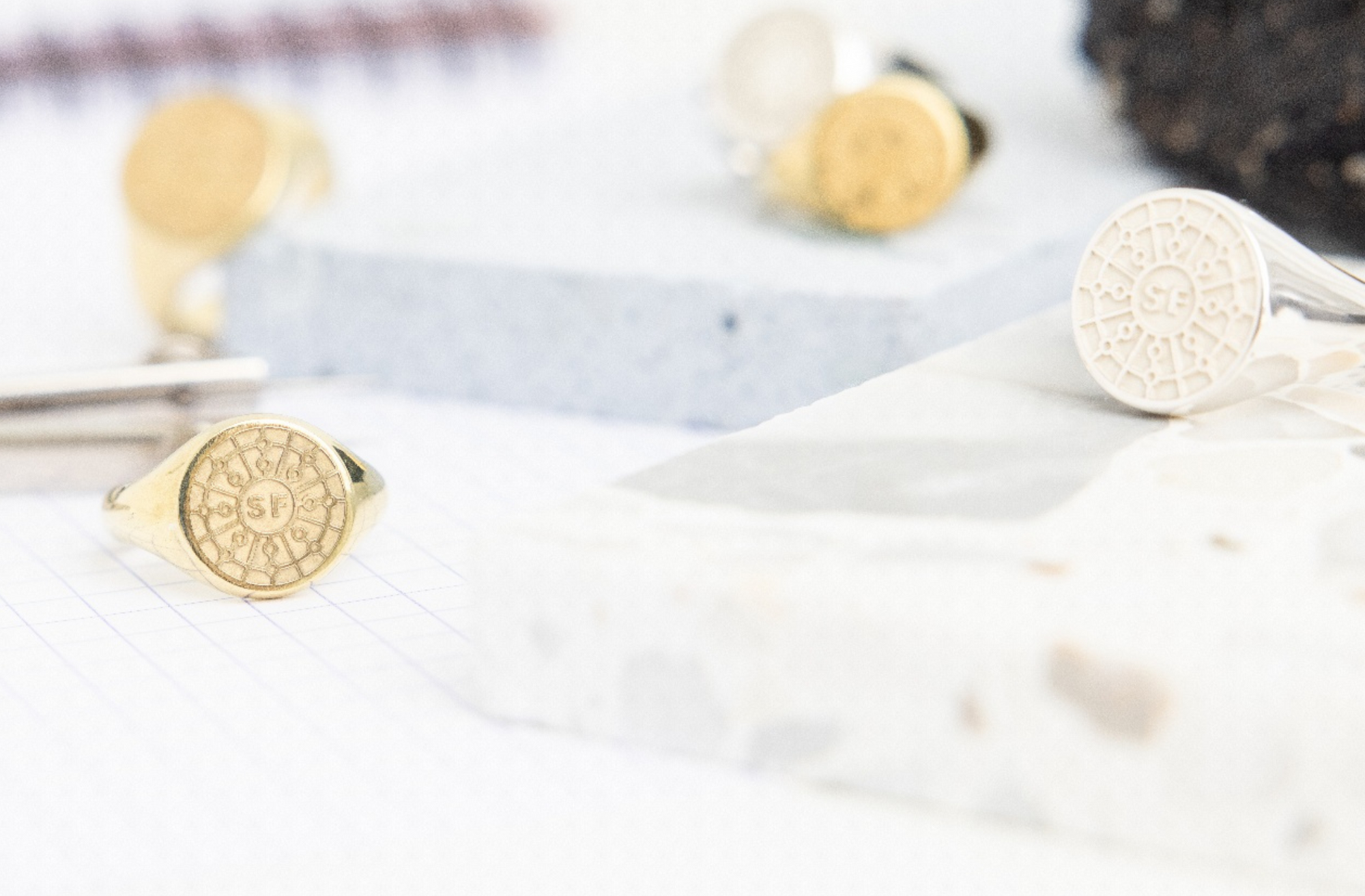 18k gold vermeil San Francisco Mini Manhole cover ring resting on a lined notebook, accompanied by drafting tools, evoking a creative and urban design atmosphere.